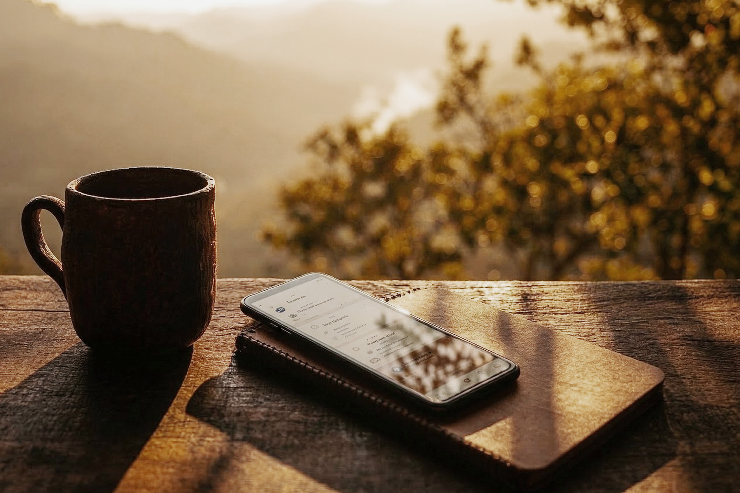 Smartphone displaying professional app interface on natural wood surface with mountain backdrop